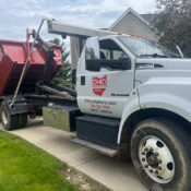 A truck dropping off a dumpster
