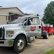 A truck and dumpster in a driveway